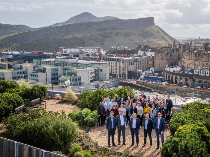An image of Forrit employees on a roof top garden with Arthurs Seat in Edinburgh in the background.